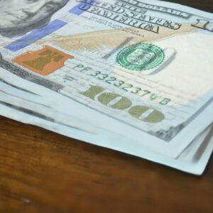 Here's a short caption: hundred dollar bills stacked on a table.